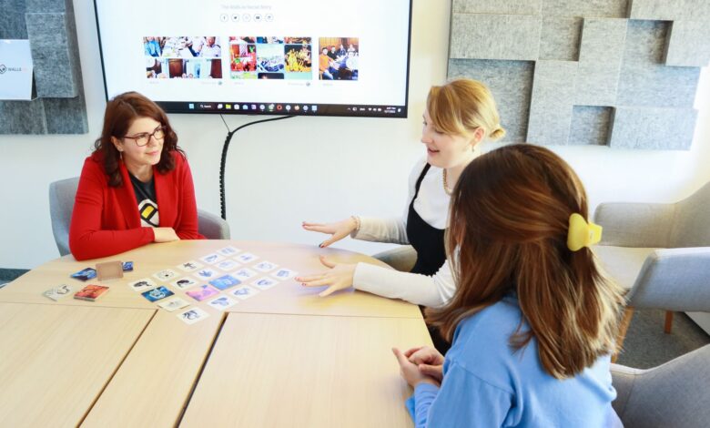 Three women discussing ideas in a modern office setting, engaging in teamwork and collaboration.