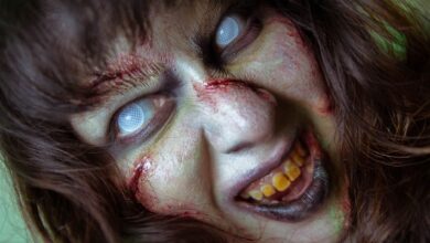 Frightening close-up of a zombie with white eyes and gory makeup, perfect for Halloween themes.