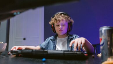 Young boy engrossed in gaming, wearing headphones, in a dimly lit room. E-sports vibe.