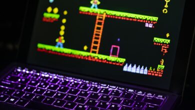 Close-up of a laptop displaying a retro video game with a neon-lit keyboard, capturing the nostalgic gaming experience.