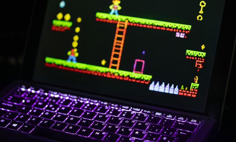 Close-up of a laptop displaying a retro video game with a neon-lit keyboard, capturing the nostalgic gaming experience.