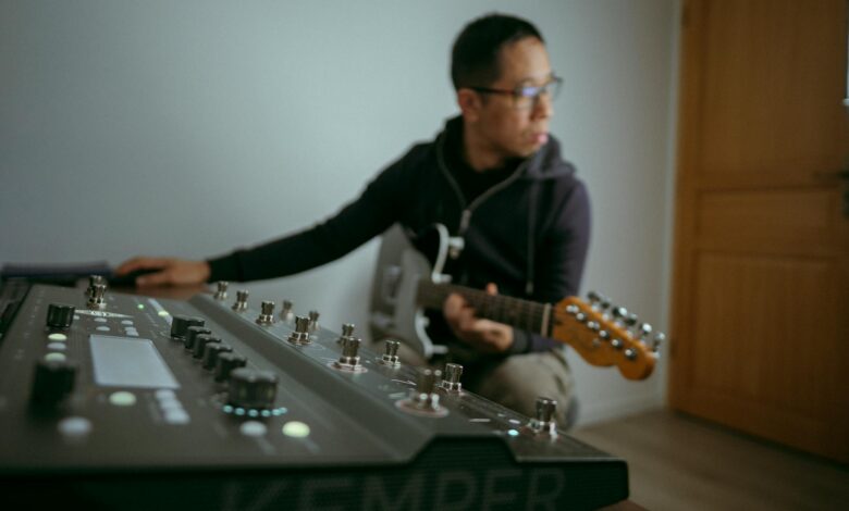 Musician playing electric guitar in a studio with a synthesizer setup in Colmar, France.