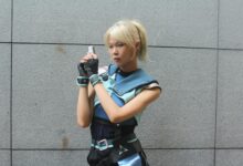 Cosplayer dressed in a futuristic outfit poses against a gray wall outdoors, exuding a sci-fi style.