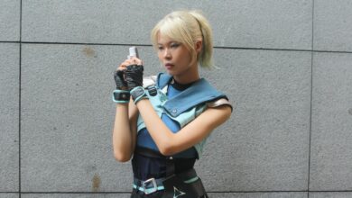 Cosplayer dressed in a futuristic outfit poses against a gray wall outdoors, exuding a sci-fi style.
