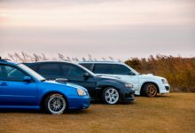 Three sporty cars parked on grass in a lineup during sunset.