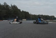 Two racers competing in a thrilling karting race on an outdoor track with forest backdrop.