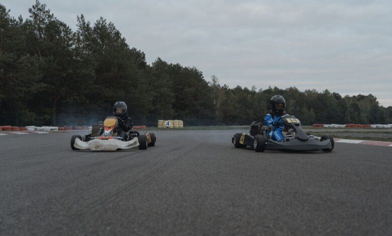Two racers competing in a thrilling karting race on an outdoor track with forest backdrop.