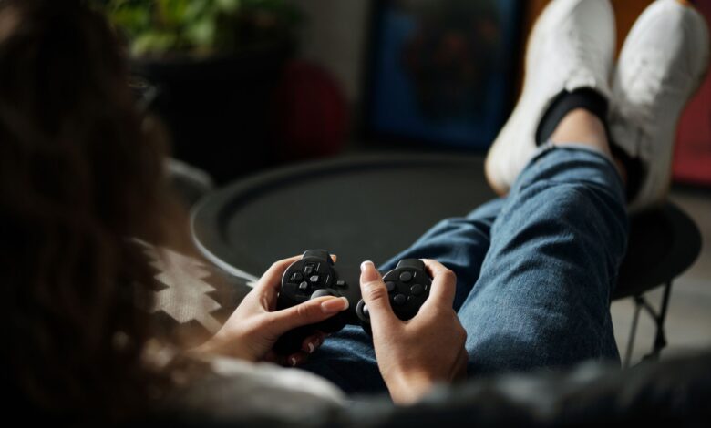 Close-up of woman gaming with a controller, feet propped up, enjoying leisure time indoors.