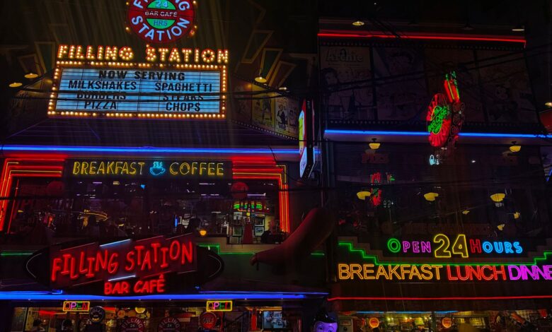 Neon signs of Filling Station Bar Cafe showcasing 24-hour service, breakfast, and coffee.