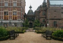Scenic view of the Rijksmuseum garden in Amsterdam featuring classic architecture and benches.