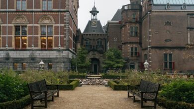 Scenic view of the Rijksmuseum garden in Amsterdam featuring classic architecture and benches.