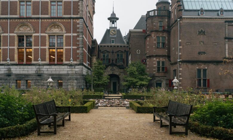 Scenic view of the Rijksmuseum garden in Amsterdam featuring classic architecture and benches.