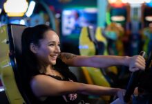 A young woman having fun playing a racing game at an arcade, smiling and engaged.