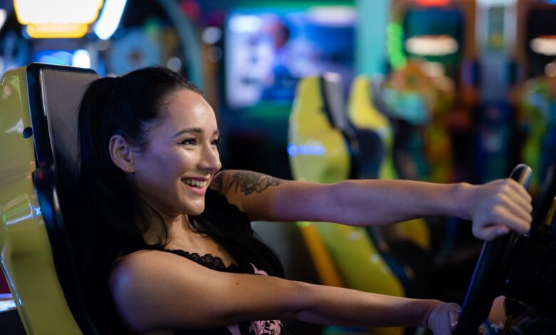 A young woman having fun playing a racing game at an arcade, smiling and engaged.