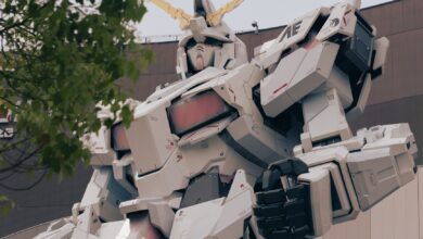 Low-angle shot of the iconic Gundam statue in Tokyo, surrounded by trees, symbolizing modernity.