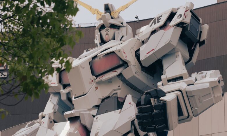Low-angle shot of the iconic Gundam statue in Tokyo, surrounded by trees, symbolizing modernity.