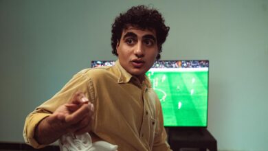 A man engaged in watching a soccer game on TV, expressing emotions.