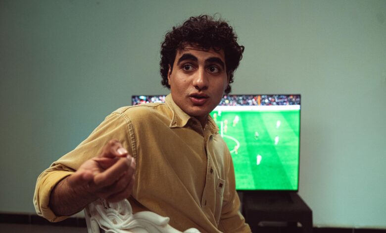 A man engaged in watching a soccer game on TV, expressing emotions.