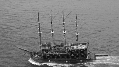 Aerial black and white photo of a pirate ship sailing the ocean, showcasing nautical adventure.