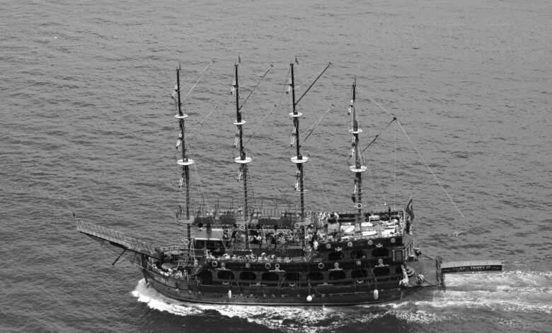 Aerial black and white photo of a pirate ship sailing the ocean, showcasing nautical adventure.