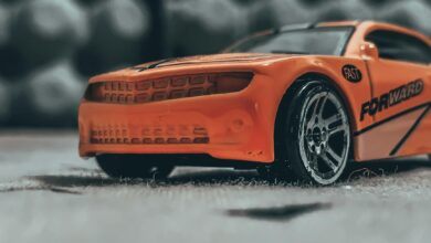 Orange contemporary toy car with sticker placed on dusty floor in soft focus