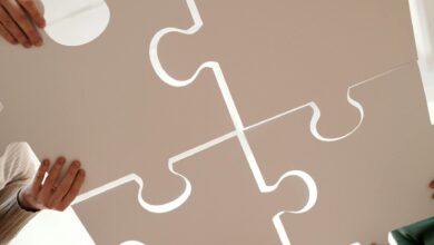 Hands of diverse individuals holding large puzzle pieces, symbolizing teamwork and unity.