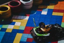 Child in go-kart racing on colorfully tiled track surrounded by tires.