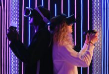 Two adults engaged in virtual reality gaming with VR headsets in a vibrant, neon-lit environment.