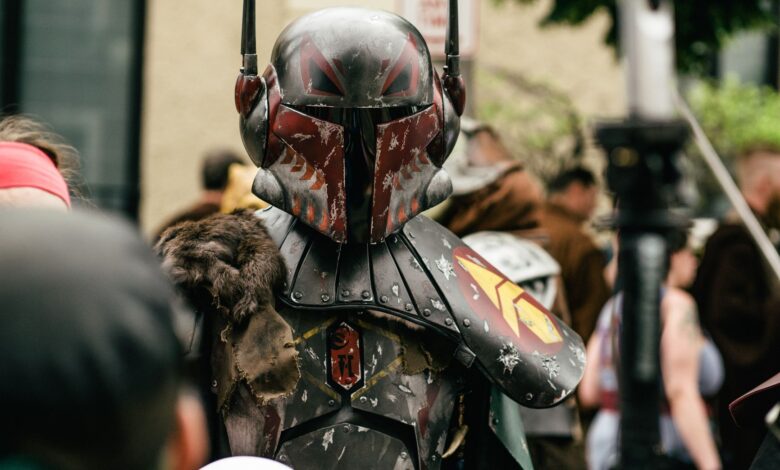 Person in detailed futuristic armor costume at a crowded outdoor cosplay event.
