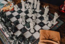Close-up of a detailed wizard-themed chess set on a wooden table with game card.