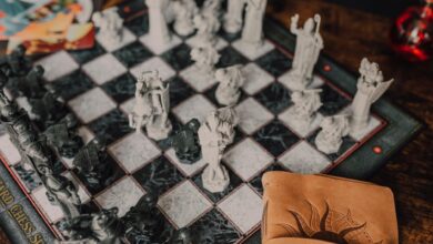 Close-up of a detailed wizard-themed chess set on a wooden table with game card.