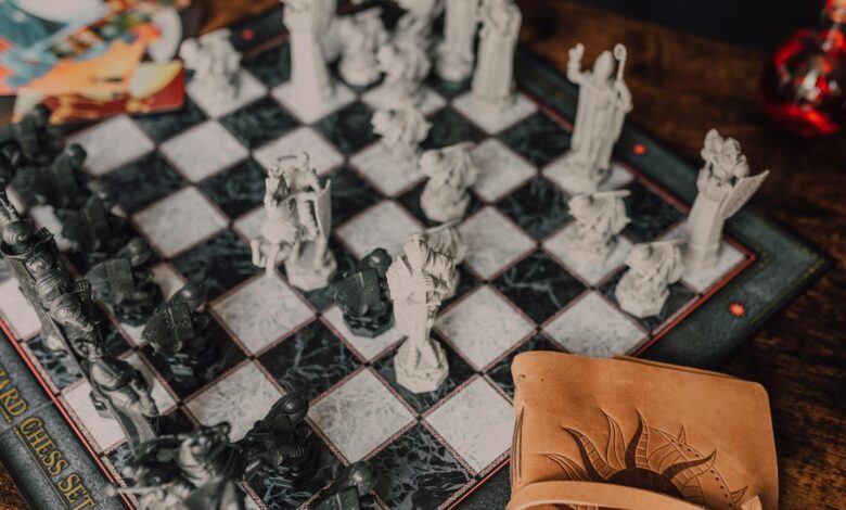 Close-up of a detailed wizard-themed chess set on a wooden table with game card.
