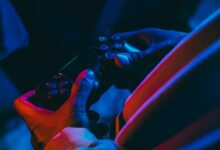 A close-up view of hands holding a gaming controller under colorful lighting, perfect for gaming enthusiasts.