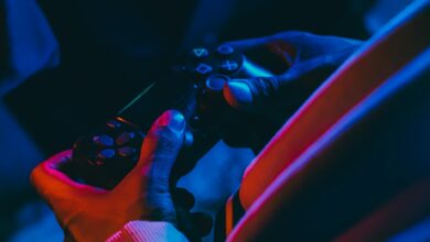 A close-up view of hands holding a gaming controller under colorful lighting, perfect for gaming enthusiasts.