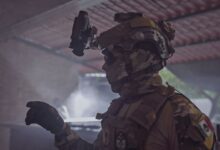 Profile of a soldier in tactical gear indoors, emphasizing readiness and security.