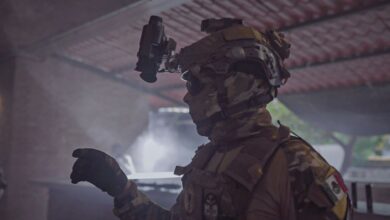 Profile of a soldier in tactical gear indoors, emphasizing readiness and security.
