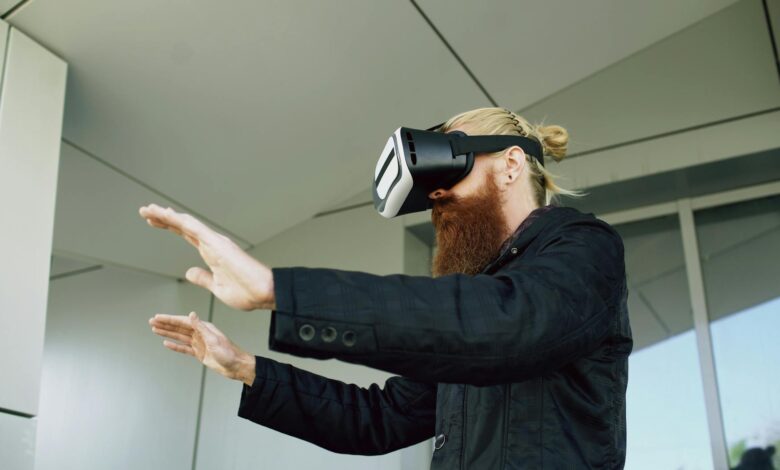 Side view of a bearded man interacting with VR headset outside modern building.
