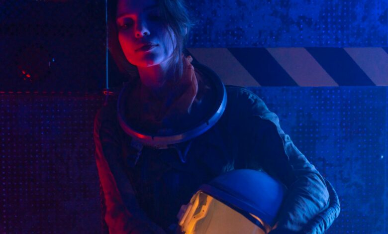 A woman astronaut in a spacesuit under vibrant red and blue lighting, evoking a futuristic, sci-fi atmosphere.