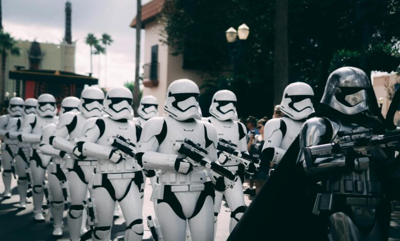 Group of stormtroopers marching outdoors during a cosplay event at a theme park.