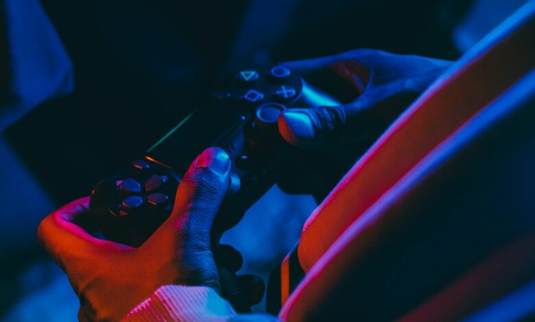 A close-up view of hands holding a gaming controller under colorful lighting, perfect for gaming enthusiasts.