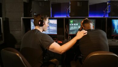 Two gamers support each other in a cyber cafe, navigating challenges together.