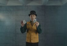 A man in steampunk attire showcasing card tricks indoors.
