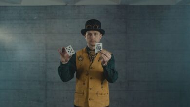 A man in steampunk attire showcasing card tricks indoors.