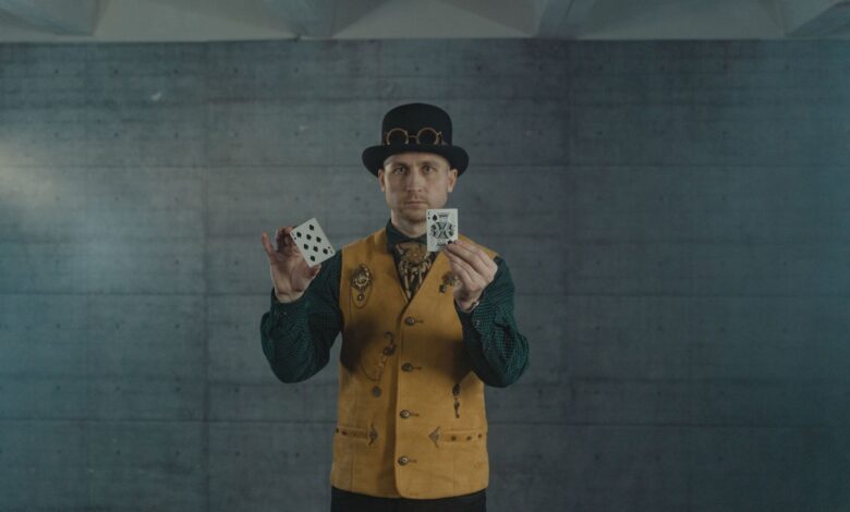A man in steampunk attire showcasing card tricks indoors.