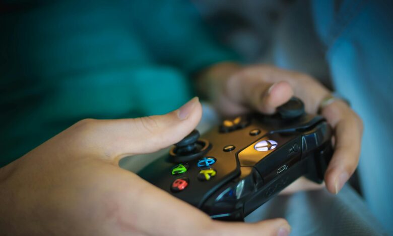 Hands gripping a modern wireless gaming controller indoors. Perfect for tech enthusiasts.