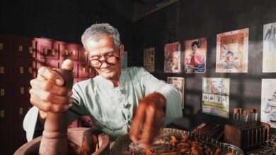 An elderly man in a traditional setting preparing herbs for Chinese medicine.