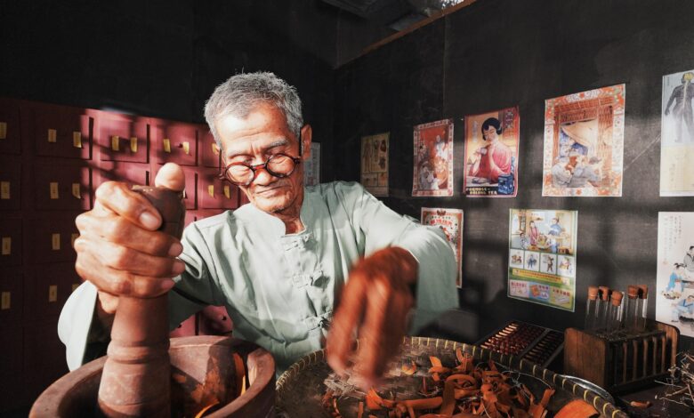 An elderly man in a traditional setting preparing herbs for Chinese medicine.