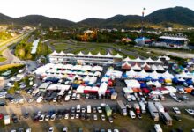 Vibrant aerial shot of a karting event with colorful tents, tracks, and vehicles under clear skies.
