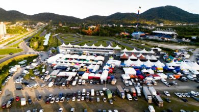 Vibrant aerial shot of a karting event with colorful tents, tracks, and vehicles under clear skies.