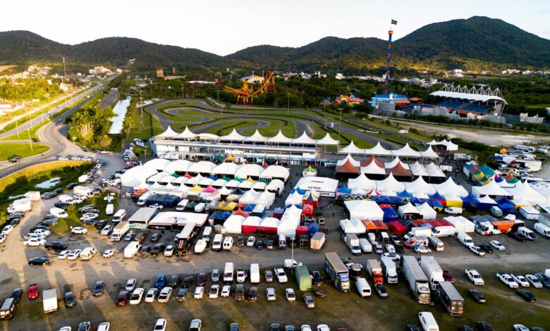 Vibrant aerial shot of a karting event with colorful tents, tracks, and vehicles under clear skies.